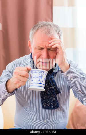 Old man drinking tea to cure bad cold or flu at home Stock Photo