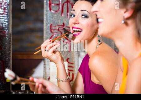 Young people eating sushi in Asia restaurant Stock Photo