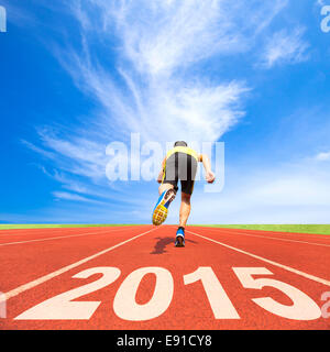 happy new year 2015. young man running on track with blue sky and cloud background Stock Photo