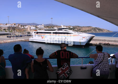 Tarifa Spain ferry passengers watch as they depart Tarifa port passing a moored Virtu Ferries ferry Stock Photo