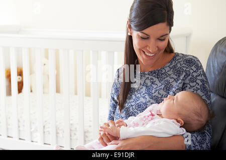 Happy Mother Sitting In Nursery With Baby Stock Photo