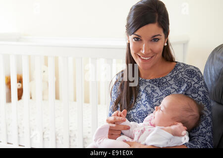 Happy Mother Sitting In Nursery With Baby Stock Photo