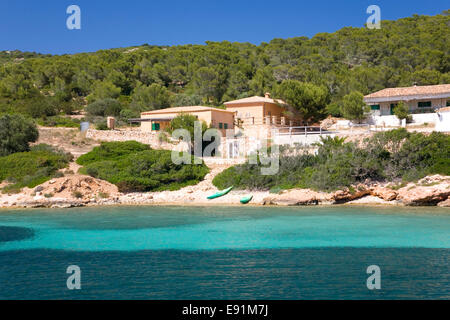 Island of Cabrera, Mallorca, Balearic Islands, Spain. View across bay to waterside houses, kayaks on shore. Stock Photo