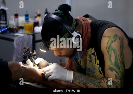 Kathmandu, Nepal. 17th Oct, 2014. A tattoo artist draws tattoo to a visitor during the 2nd International Nepal Inked Tattoo and Lifestyle Convention at Kathmandu, Nepal, on Oct. 17, 2014. 100 tattoo artists from different countries took part in the convention which will run for three days. © Pratap Thapa/Xinhua/Alamy Live News Stock Photo