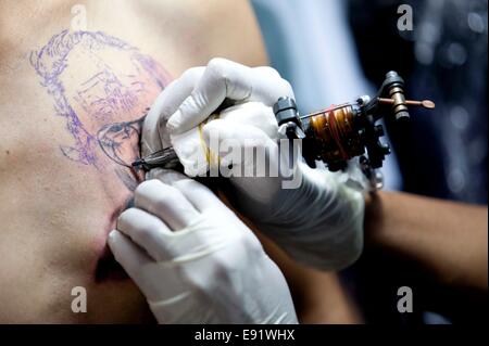 Kathmandu, Nepal. 17th Oct, 2014. A tattoo artist draws tattoo to a visitor during the 2nd International Nepal Inked Tattoo and Lifestyle Convention at Kathmandu, Nepal, on Oct. 17, 2014. 100 tattoo artists from different countries took part in the convention which will run for three days. © Pratap Thapa/Xinhua/Alamy Live News Stock Photo