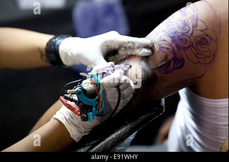 Kathmandu, Nepal. 17th Oct, 2014. A tattoo artist draws tattoo to a visitor during the 2nd International Nepal Inked Tattoo and Lifestyle Convention at Kathmandu, Nepal, on Oct. 17, 2014. 100 tattoo artists from different countries took part in the convention which will run for three days. © Pratap Thapa/Xinhua/Alamy Live News Stock Photo