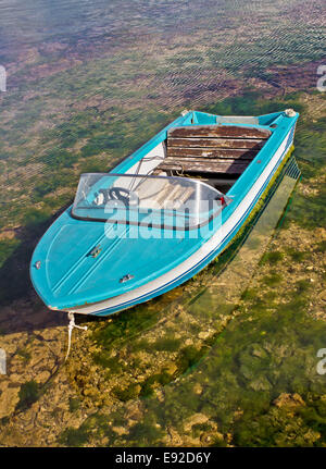 Blue boat tied up in shallow sea Stock Photo