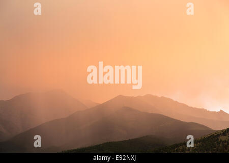 Rain clouds at sunset over mountains Stock Photo