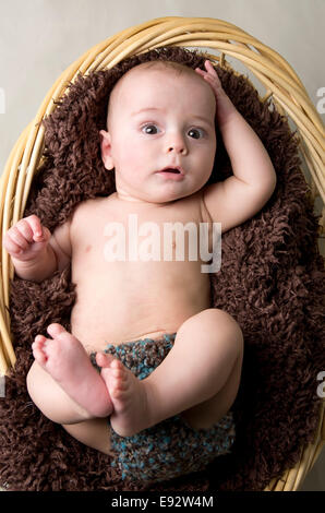 9 month old baby boy in a basket, laying on his back Stock Photo