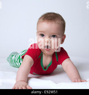 9 month old baby boy holding his head up wearing Christmas colors looking shocked and stunned Stock Photo