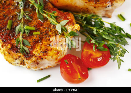 Fresh roasted pork meat steaks served with tomato and fresh herbs over white background. Top view. Stock Photo