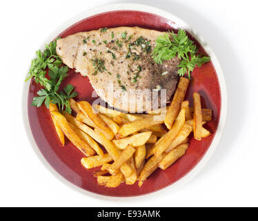 Swordfish steak cooked on a plate with french fries and a parsley and garlic butter sauce seen from above Stock Photo