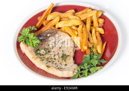 Swordfish steak cooked on a plate with french fries and a parsley and garlic butter sauce seen from the side Stock Photo