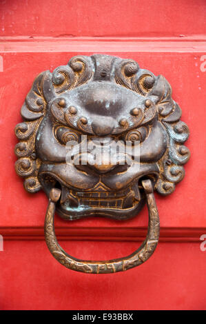 Vertical close up of brass door knocker on a bright red door. Stock Photo