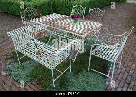 Elegant metal table and chairs with herb flooring beneath at Jennifer Stratton's garden in Codford, Wiltshire Stock Photo