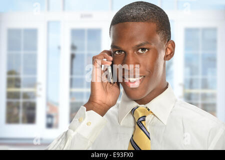 African American businessman using cellphone with office building in background Stock Photo
