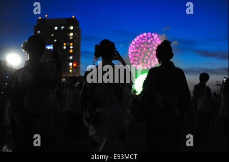 Young women dressed in 'yukata' photograph the fireworks at the Adachi Fireworks festival. Stock Photo