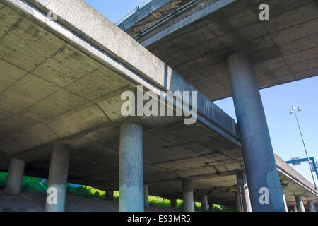 Elevated freeway concrete bridges criss-cross as seen from below. Stock Photo