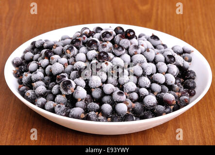 heap of frozen black currant covered with hoarfrost in the white plate Stock Photo