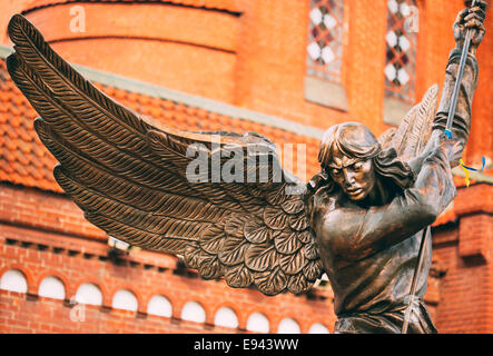 Statue of Archangel Michael with outstretched wings, thrusting spear into dragon before Catholic Church of St. Simon and Stock Photo