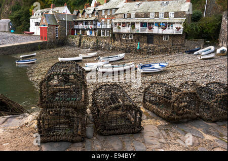 Lobster pots lined up on the harbour wall, fishing boats in the background. Stock Photo