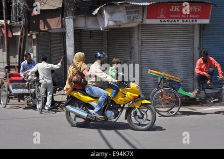 Indian man, woman and child riding a motorbike through the back streets of Delhi Stock Photo