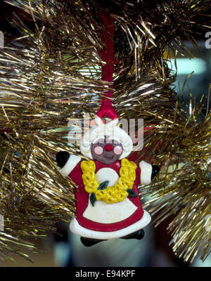 A colorful bread-dough Hawaiian Santa Claus ornament with a lei of yellow flowers around his neck hangs in a Christmas tree in Honolulu, Hawaii, USA. Stock Photo