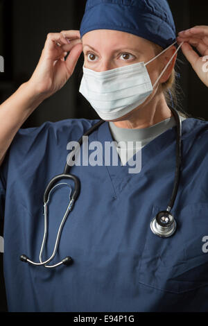 Attractive Female Doctor or Nurse Putting on Protective Face Mask. Stock Photo