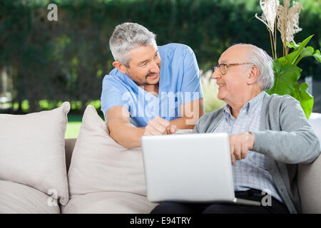Smiling Nurse And Senior Man Using Laptop Stock Photo