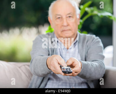 Senior Man Using Remote Control While Sitting On Couch Stock Photo