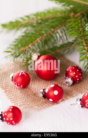 Red themed Christmas place setting with a colorful red napkin on white plates decorated with small red Xmas baubles and burning Stock Photo