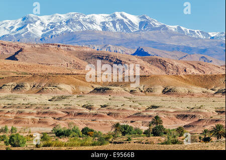 ATLAS MOUNTAINS OF MOROCCO COVERED IN SNOW WITH AN OASIS OF PALM TREES IN THE FOOTHILLS Stock Photo