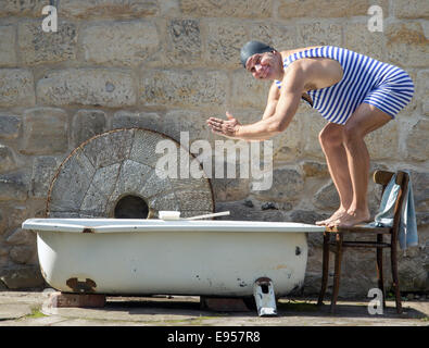 man in retro swimsuit jumps to the outdoor bathtub Stock Photo
