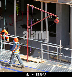 Fall prevention restraint system in use by workman on raised platform on construction site Stock Photo