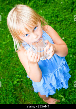 Cute little girl drinking water outdoors Stock Photo