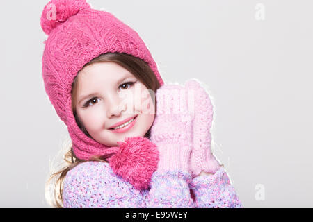 Happy little child in winter clothes, cute baby girl in woolen accessories, studio,white background. Kid in winter hat gloves Stock Photo