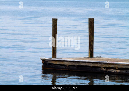 A single old, weathered, floating, boat dock made of wood planks and posts at Lake Murray, SC on an overcast day. Stock Photo