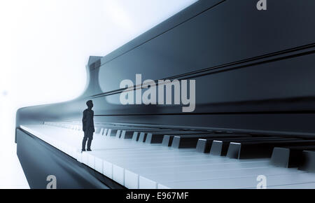 Tiny man standing on a classical piano keyboard Stock Photo