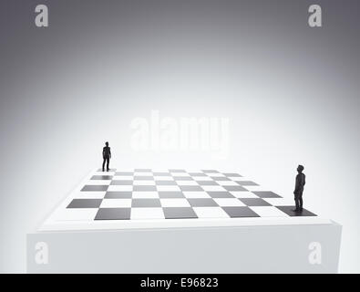 Two tiny figures standing on a chess board - conflict and competition concept illustration Stock Photo