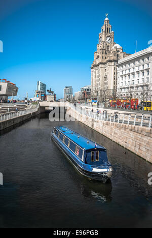 A narrowboat cruising along the Liverpool central canal link at Pier Head with the Liver Building and ferry terminal in the backg Stock Photo