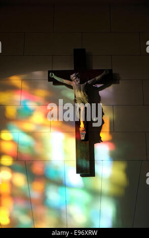 colorful stained glass window reflections on wall and crucifix Stock Photo