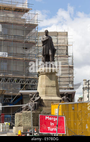 The George Stephenson memorial near Newcastle Central Station, surrounded by the signs of construction work and scaffolding shrouded buildings. Stock Photo