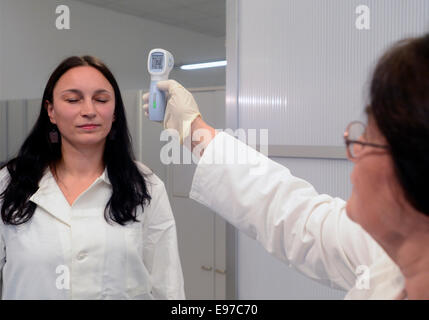 Prague, Czech Republic. 21st Oct, 2014. Medical staff demonstrates taking the temperature of a passenger at the Vaclav Havel Airport in Prague, Czech Republic, October 21, 2014. Czech Republic introduces screening of passengers in efforts to prevent the spread of Ebola. Credit:  Roman Vondrous/CTK Photo/Alamy Live News Stock Photo