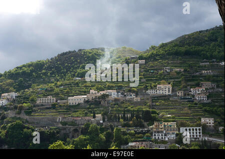 Villas, lemon groves, cypress trees, bonfire smoke and houses on the cliffs close to Amalfi from a boat in the Bay of Salerno in Stock Photo