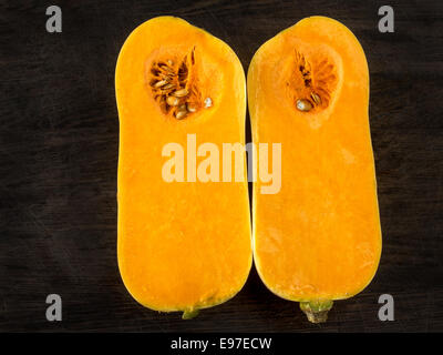 One butternut squash cut in halves on a dark background Stock Photo