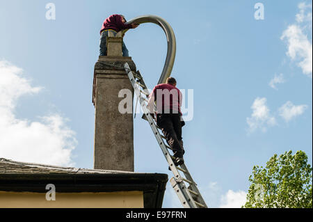 Inserting a flexible chimney liner into the chimney of an old house, UK Stock Photo