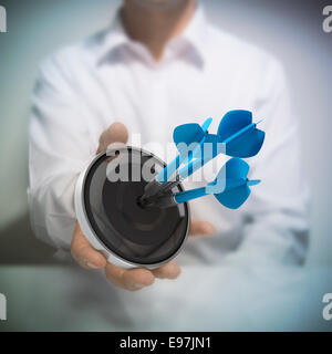 Man holding on black target with three blue darts hitting the center. Concept image for illustration of Marketing and advertisin Stock Photo