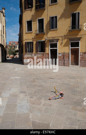 A child's push scooter left lying in Ramo Va in Campo, Santa Croce, Venice, Italy. Stock Photo