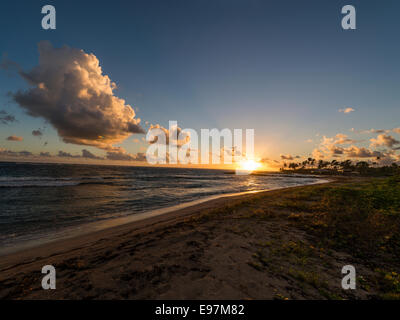 Landscape - Sun rising behind a cloud formation in the background with Long Haul Bay beach and Caribbean sea in foreground. Stock Photo