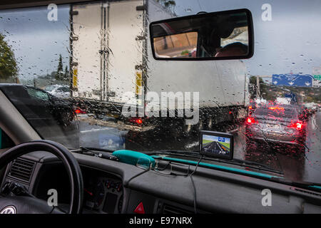 Truck overtaking cars on highway during heavy rain shower seen from inside of vehicle with big raindrops on windscreen Stock Photo